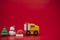 Toy of Christmas tree, gift box on truck, snowman and Santa Claus hat on red background