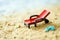 Toy deck chair and small blue flip-flops on the sand