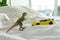Toy dinosaur and car on parent`s bed, depicting family home and parenting life. White linens in background