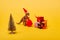 Toy dinosaur in santa hat and sack beside pine with gifts