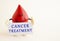 A toy drop of blood holds a white paper card with the inscription CANCER TREATMENT.