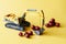 Toy excavator works and loads fresh red cherries. Yellow background. The concept of agricultural work, fruit harvesting. Toy world