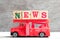 Toy fire ladder truck hold block in word news on wood background