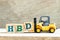 Toy forklift hold block D to complete word HBD Abbreviation of happy birthday on wood background