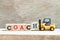 Toy forklift hold block h in word coach on wood background