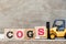 Toy forklift hold block S in word COGS Abbreviation of Cost of goods sold on wood background