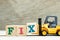 Toy forklift hold block x to complete word fix on wood background