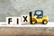 Toy forklift hold block x to complete word fix on wood background