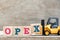 Toy forklift hold block x in word opex abbreviation of operating expense on wood background