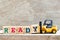 Toy forklift hold block y to complete word ready on wood background