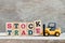 Toy forklift hold lette block k,e to complete word stock trade on wood background