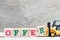 Toy forklift hold letter block R to complete word offer on wood background