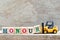 Toy forklift hold letter block r to word honour on wood background