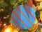 Toy in the form of a bright blue circle with a red stripe on a Christmas tree with garland.