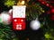 A toy in the form of a red house hangs on a Christmas tree. Christmas tree decoration in the form of a winter house hanging on a