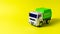 The toy is a garbage truck green with a white body on a yellow background banner with a place for text for a toy store. Children`