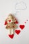 Toy girl angel holds a valentine in his hands and thinks about her lover on a white background