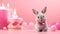 A toy grey fluffy rabbit with gifts on a pink background. Cute bunny with a pink bow. The concept of birthday greetings