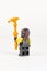 Toy hero Cole in a black kimono with a golden weapon earthquake scythe from a set of lego ninjago on a white background
