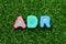 Toy letter in word ADR Abbreviation of Adverse drug reaction on green grass background