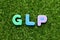 Toy letter in word GLP Abbreviation of Good laboratory practice on green grass background