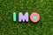 Toy letter in word  IMO Abbreviation of in my opinion on green grass background