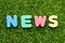Toy letter in word news on green grass background