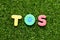 Toy letter in word TOS abbreviation of Terms Of Service on green grass background