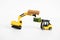 A toy loader or construction crane in bright yellow carries a piece of cucumber and a piece of black freshly baked bread. Close-up