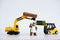 A toy loader or construction crane in bright yellow carries a piece of cucumber and a piece of black freshly baked bread. Close-up