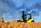 Toy loader on a pile of sand against a blue sky. Loading and construction work.