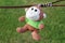 The toy monkey is left hanging on the barbed wire on a green grass background