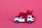 Toy new car gift with red bow on red background. Concept rental, auto dealership, copy space