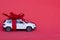Toy new car gift with red bow on red background. Concept rental, auto dealership, copy space