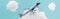 Toy plane flying among white fluffy clouds made of cotton wool isolated on blue, panoramic shot