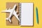 Toy plane with a notebook on a yellow background, top view