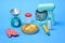 toy plastic cooking machine to prepare dough, bottle of milk, rolling pin, scales, oven glove and finished cakes on blue pastel