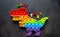 Toy pop it dinosaur rainbow colors on a black background with multicolored letters and the inscription-Anti-stress on the back