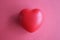 Toy rubber heart lying on red background closeup top view