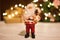 Toy Santa Claus on the background of gift boxes and a Christmas wreath with a luminous garland