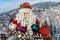 Toy Santa Claus with Christmas decorations against the backdrop of a winter landscape with mountains covered with forests