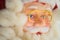 Toy Santa Claus face in golden glasses and red hat closeup