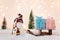 Toy snowman pulling small wooden sleigh with a Christmas gifts.