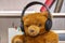 Toy teddy bear with headphones on a neutral background in a room. Concept: Listening to music.