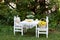 Toy Teddy bear sitting on white chair and cups of tea at the white small table. Children play area in garden. Outdoors wooden chai
