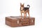 Toy-terrier standing on travel suitcase.