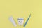 Toy tooth, blue toothbrush and toothpaste on yellow background