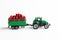 A toy tractor carries red fresh cranberries in a trailer. White background. Agricultural work and harvesting concept