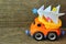 Toy truck carrying hand made paper christmas tree against rough wooden background. Side view. Christmas tree recycle or disposal,