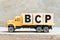Toy truck hold letter block in word BCP abbreviation business continuity plan on wood background